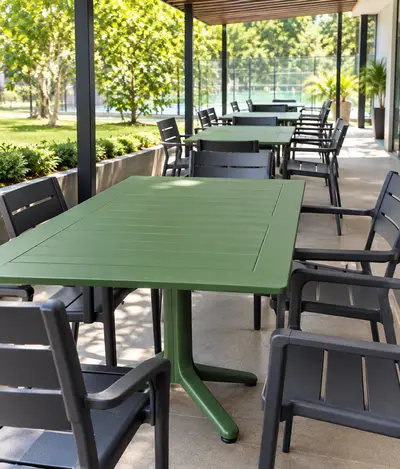 Terraza moderna con mesas verdes y jardín